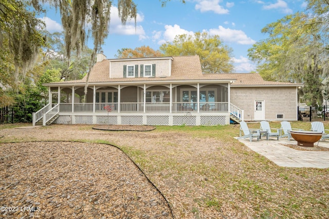 rear view of property featuring a patio, a chimney, a sunroom, fence, and a fire pit