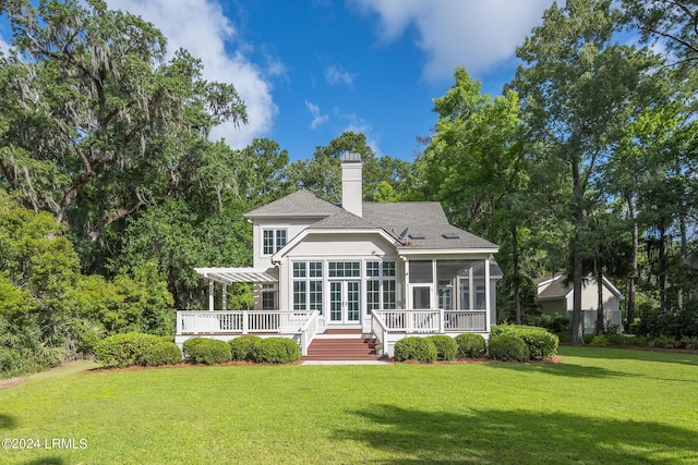 rear view of house featuring a sunroom, a lawn, and a pergola