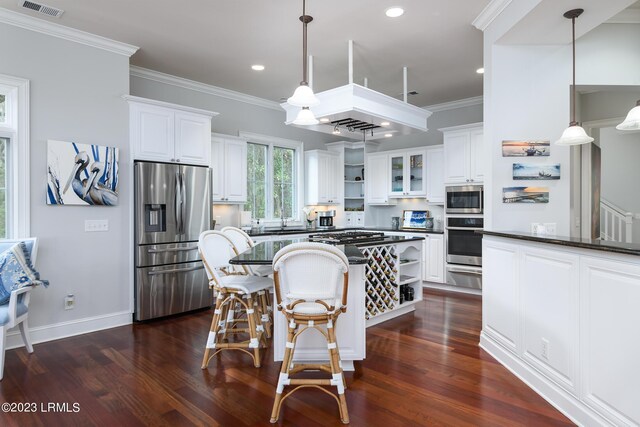 kitchen featuring white cabinetry, ornamental molding, appliances with stainless steel finishes, and hanging light fixtures