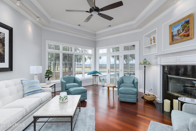 living room with built in shelves, a high end fireplace, ornamental molding, and dark hardwood / wood-style floors