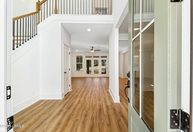 foyer with ceiling fan, a towering ceiling, and light hardwood / wood-style flooring