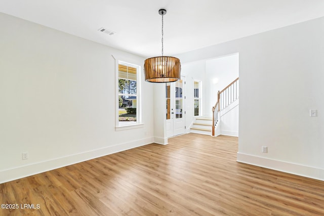 unfurnished dining area featuring a chandelier and light hardwood / wood-style floors