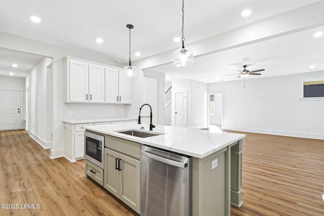 kitchen with built in microwave, white cabinetry, an island with sink, sink, and stainless steel dishwasher