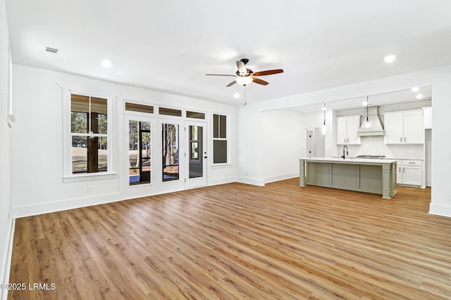 unfurnished living room with sink, light hardwood / wood-style flooring, and ceiling fan