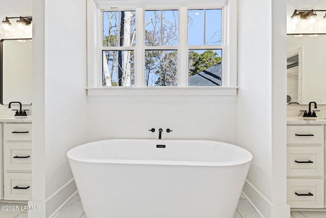 bathroom with vanity, a tub to relax in, and a healthy amount of sunlight