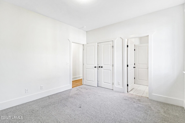 unfurnished bedroom featuring light colored carpet and a closet