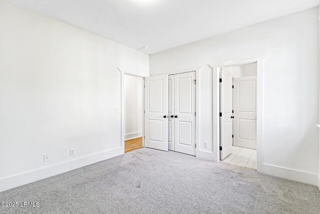 unfurnished bedroom featuring light colored carpet and a closet