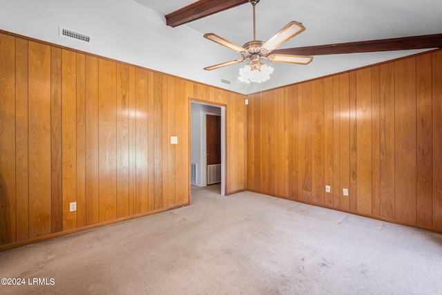 carpeted spare room featuring lofted ceiling with beams, wooden walls, and ceiling fan