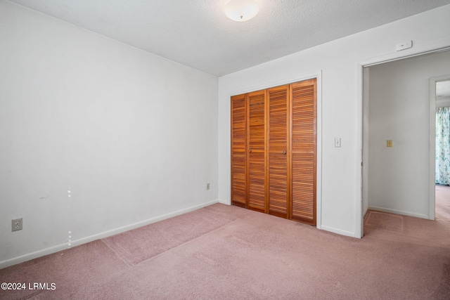 unfurnished bedroom featuring light carpet, a textured ceiling, and a closet