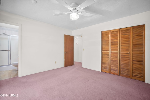 unfurnished bedroom featuring ceiling fan, connected bathroom, light colored carpet, and a closet