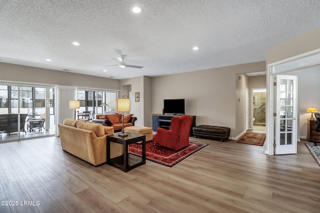 living room with light wood-type flooring, ceiling fan, a textured ceiling, and recessed lighting