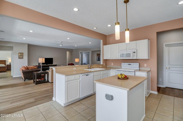 kitchen featuring light countertops, white cabinets, a sink, light tile patterned flooring, and white appliances