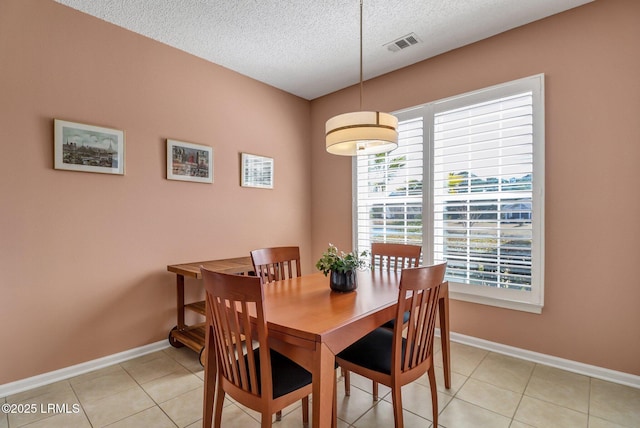 dining space featuring a textured ceiling, baseboards, visible vents, and a healthy amount of sunlight