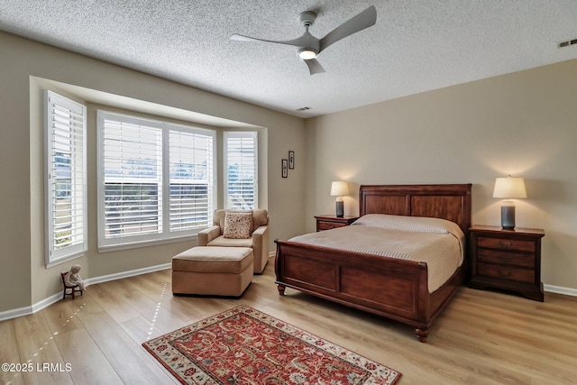 bedroom with light wood-style floors, ceiling fan, baseboards, and a textured ceiling