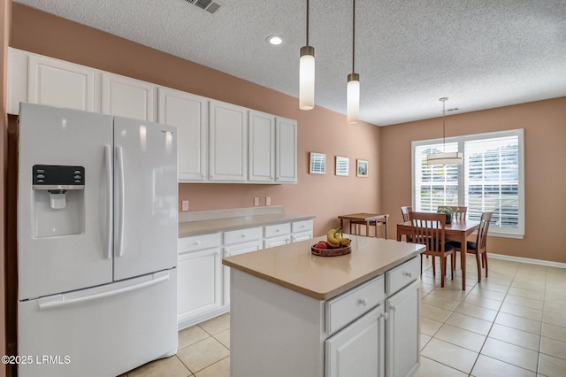 kitchen featuring light tile patterned floors, light countertops, hanging light fixtures, white cabinetry, and white fridge with ice dispenser