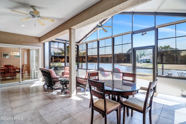 sunroom with ceiling fan, a water view, and vaulted ceiling with beams