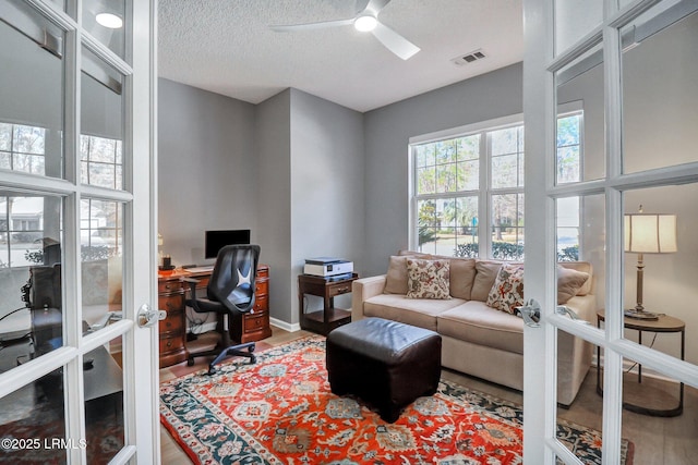 office space with a textured ceiling, ceiling fan, visible vents, baseboards, and french doors