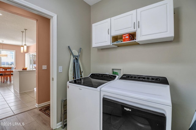 laundry area featuring washing machine and dryer, cabinet space, and baseboards