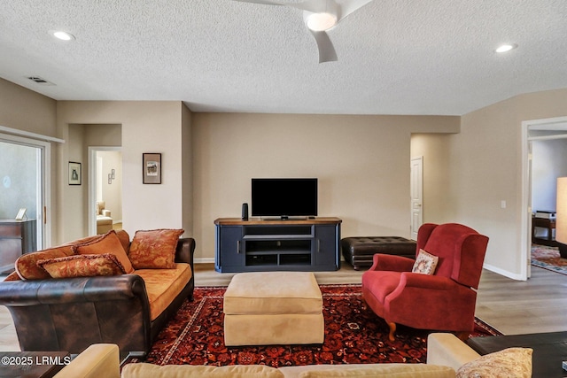 living area with baseboards, visible vents, ceiling fan, wood finished floors, and a textured ceiling