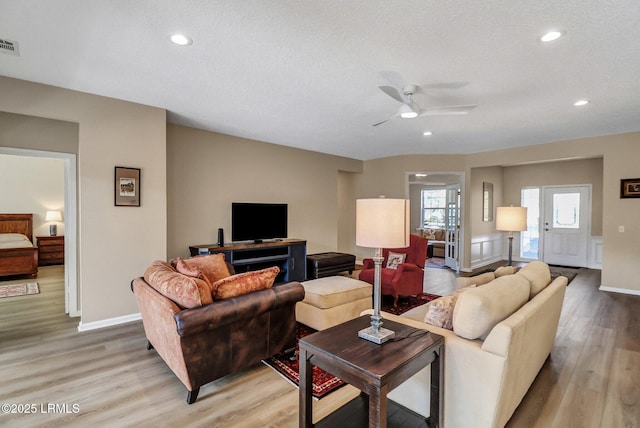 living area with light wood finished floors, ceiling fan, a textured ceiling, and recessed lighting