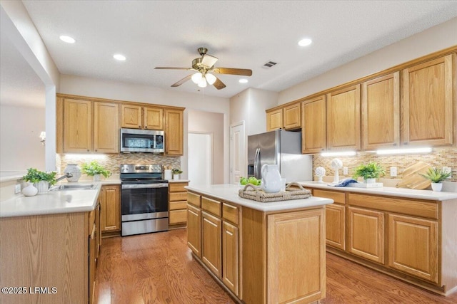 6 Pinyon Dr, Bluffton, SC 29909 - kitchen featuring stainless steel appliances, wood finished floors, a ceiling fan, decorative backsplash, and light countertops