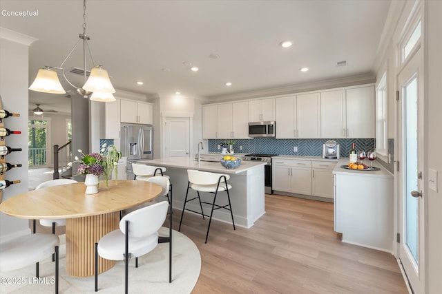 425 Parkside Commons, Bluffton, SC 29910 - kitchen with stainless steel appliances, decorative backsplash, a kitchen island with sink, white cabinets, and recessed lighting