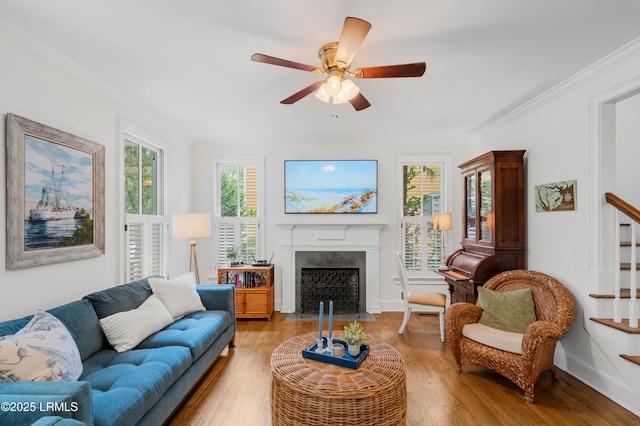 14 Fraser St, Beaufort, SC 29907 - living room with stairs, crown molding, light wood-style flooring, a ceiling fan, and a fireplace with flush hearth