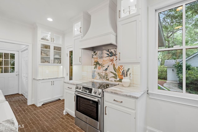 14 Fraser St, Beaufort, SC 29907 - kitchen featuring stainless steel electric stove, premium range hood, brick patterned flooring, backsplash, and white cabinets