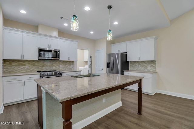 kitchen with appliances with stainless steel finishes, a kitchen island with sink, and white cabinets