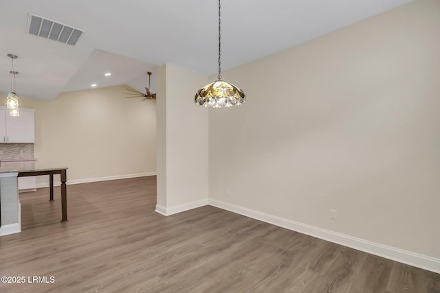 unfurnished dining area featuring ceiling fan, lofted ceiling, and hardwood / wood-style floors