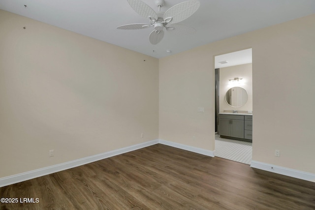 unfurnished bedroom with ceiling fan, ensuite bathroom, dark hardwood / wood-style flooring, and sink