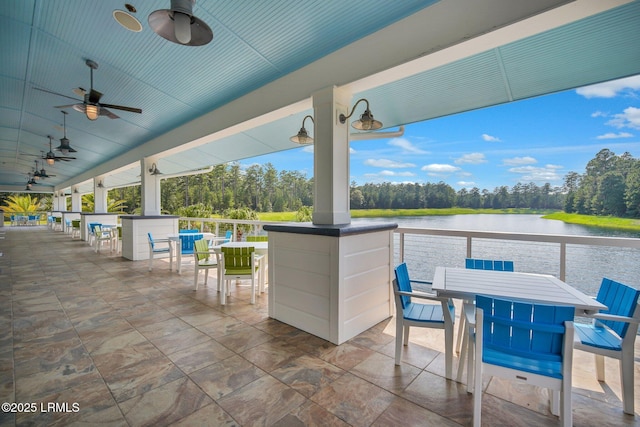 view of patio / terrace with a water view, ceiling fan, and exterior bar