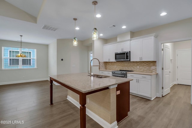 kitchen featuring sink, appliances with stainless steel finishes, white cabinetry, a kitchen island with sink, and decorative light fixtures