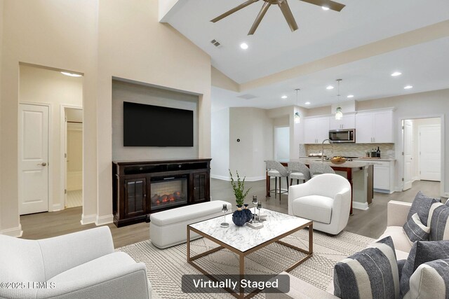 kitchen with white cabinetry, a center island with sink, appliances with stainless steel finishes, pendant lighting, and decorative backsplash