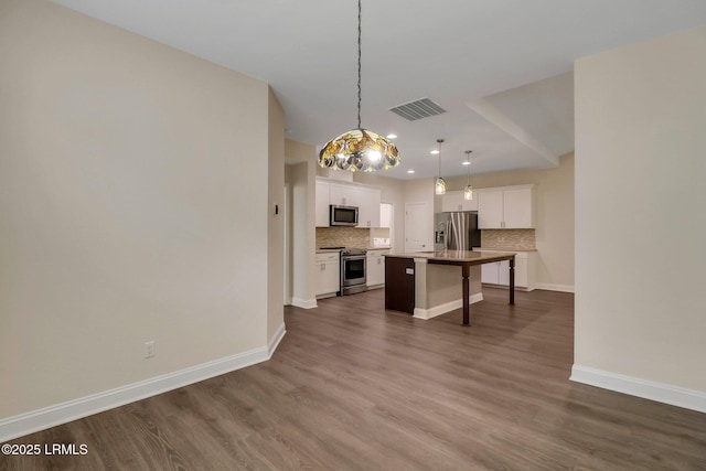 kitchen with appliances with stainless steel finishes, a center island, hanging light fixtures, and white cabinets