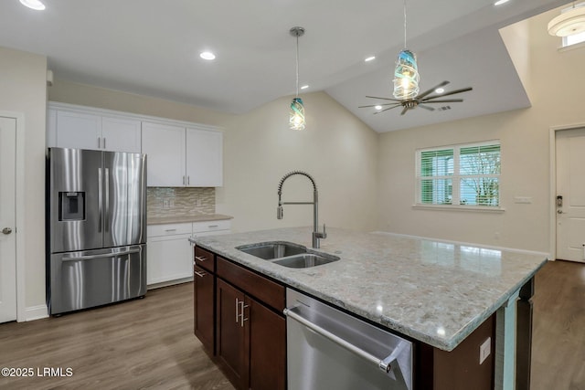 kitchen with appliances with stainless steel finishes, sink, backsplash, white cabinets, and light stone counters