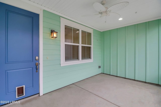 view of exterior entry featuring ceiling fan and board and batten siding