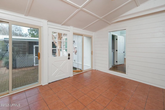 entryway with lofted ceiling, tile patterned flooring, and wood walls