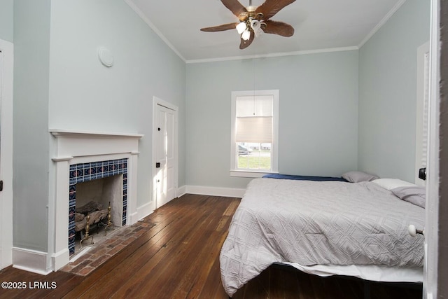 unfurnished bedroom with a tile fireplace, crown molding, dark wood-type flooring, and ceiling fan