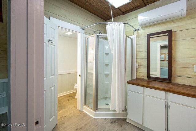 bathroom with hardwood / wood-style flooring, wooden walls, a wall unit AC, and curtained shower