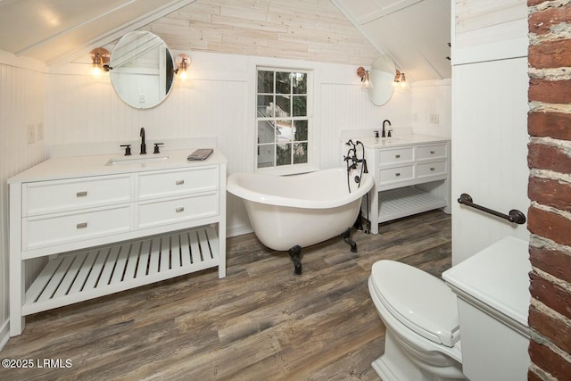 bathroom featuring hardwood / wood-style flooring, a bathtub, vanity, vaulted ceiling, and toilet