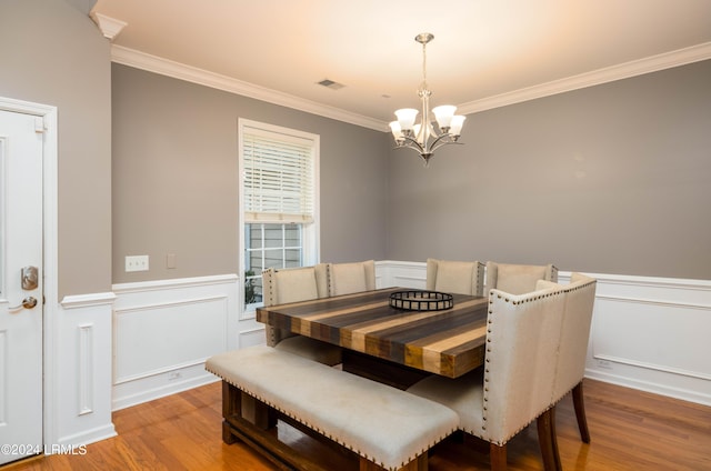 dining space featuring hardwood / wood-style flooring, crown molding, and a notable chandelier