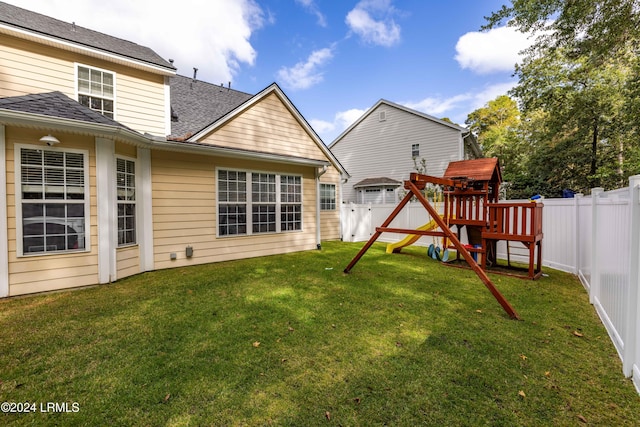 back of property with a yard and a playground