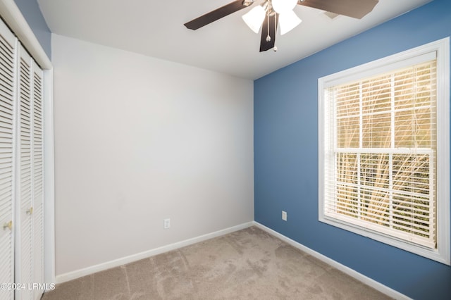 unfurnished bedroom with ceiling fan, light carpet, and a closet