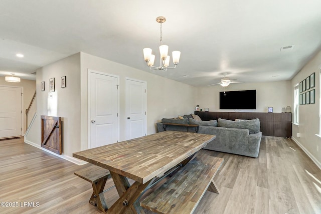 dining area with light wood-style flooring, ceiling fan with notable chandelier, visible vents, baseboards, and stairs