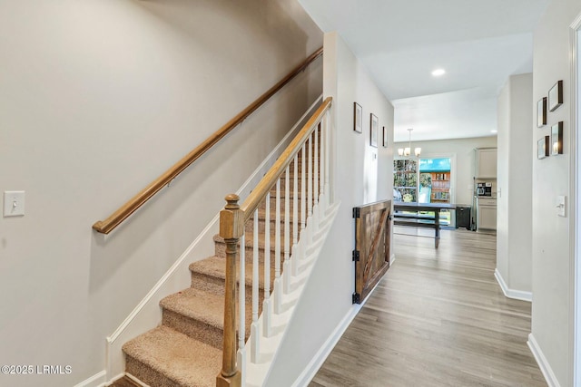 stairs featuring a chandelier, recessed lighting, wood finished floors, and baseboards