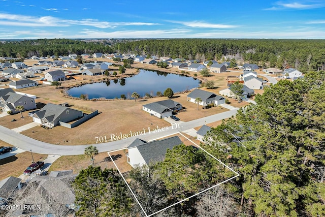 birds eye view of property with a forest view, a water view, and a residential view