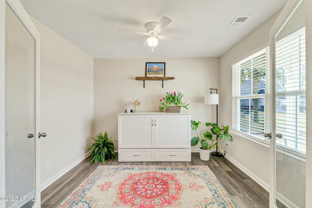 living area with dark wood-type flooring, baseboards, and a ceiling fan