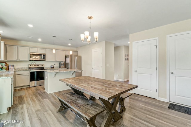 dining space featuring baseboards, light wood finished floors, an inviting chandelier, and recessed lighting