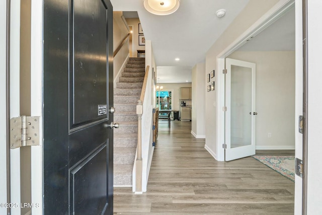 foyer entrance with stairway, light wood-style flooring, and baseboards